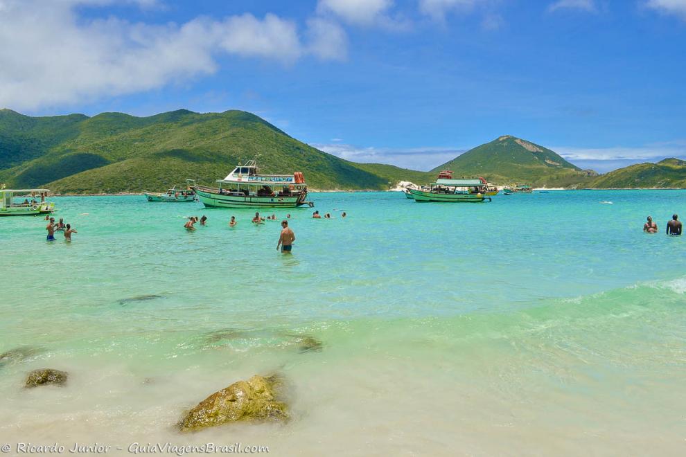 Imagem de turistas mergulhando em volta dos barcos na Praia do Pontal do Atalaia.